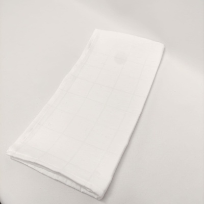 Guardanapo de tecido branco dobrado com padrão de quadrados