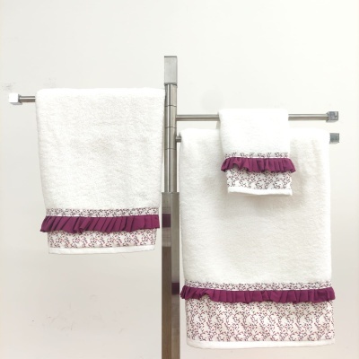Conjunto de toalhas brancas com decoração roxa penduradas em suporte metálico