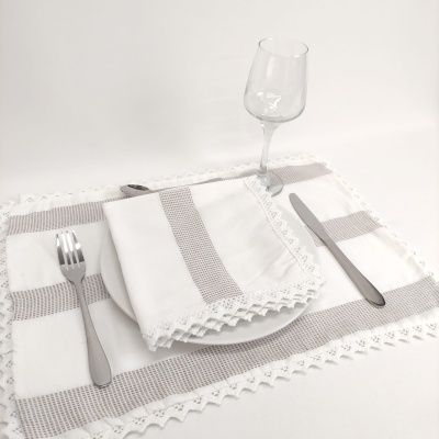 Jogo americano e guardanapo em tecido branco com faixas cinza e renda, prato branco, talheres metálicos e copo de vidro