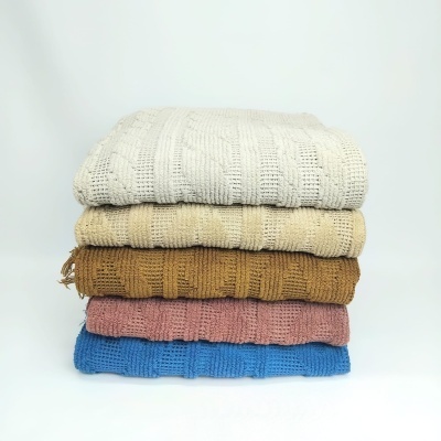 Cinco mantas empilhadas de malha com padrão quadriculado e várias cores