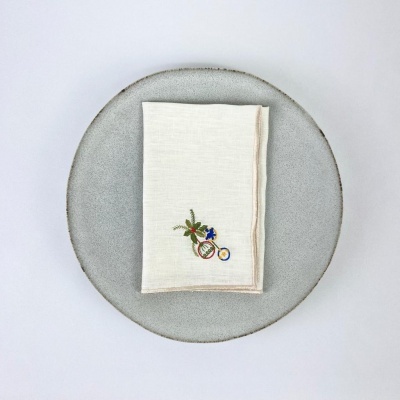 Guardanapo bordado em prato cinza sobre fundo branco