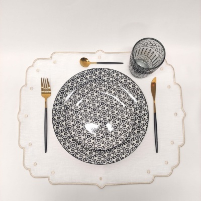 Conjunto de prato com talheres dourados e copo transparente em individual branco