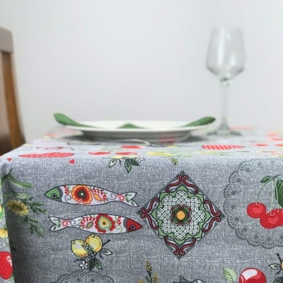 Toalha de mesa cinza com padrões coloridos de peixes, cerejas, flores e borboletas