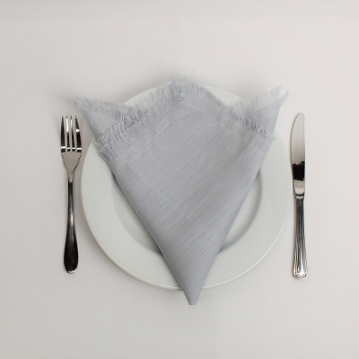 Prato branco com guardanapo cinzento e talheres de metal