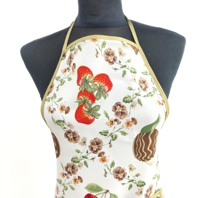 Avental branco com padrão colorido de morangos, flores e objetos, apresentado em manequim preto.