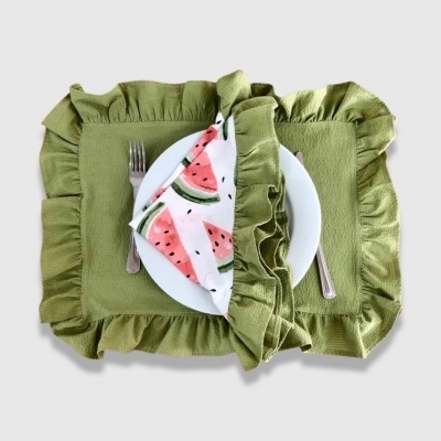 Individuais de mesa verdes com folhos, prato branco e guardanapo com estampado de melancia