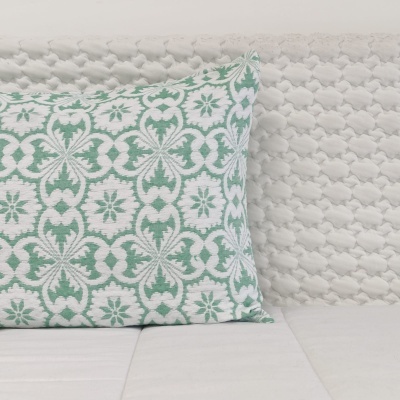 Travesseiro decorativo verde e branco sobre sofá branco com textura