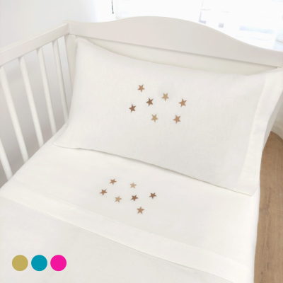 Cama infantil branca com roupa de cama branca com pequenas estrelas douradas