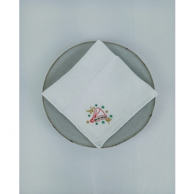 Guardanapo branco com bordado de sino vermelho e palavra 'XMAS' sobre prato cinza