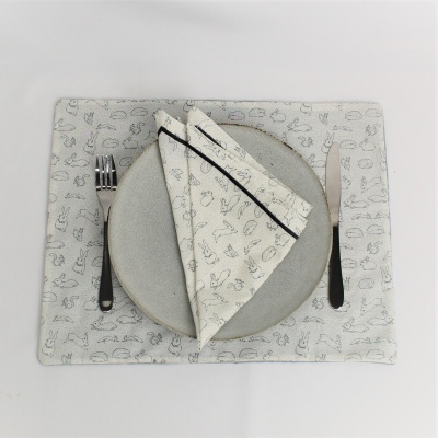 Conjunto de mesa com base e guardanapo bege claro com padrão de utensílios, prato cinzento, talheres pretos