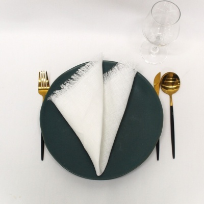 Conjunto de jantar com prato verde, guardanapo branco e talheres dourados e pretos