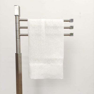 Toalha branca pendurada num suporte metálico prateado para toalhas