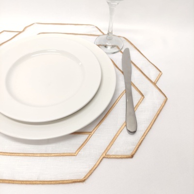 Conjunto de loiça com pratos brancos, faca, taça e sousplats brancos com bordado dourado