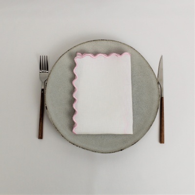 Talheres de madeira ao lado de prato cinza com guardanapo branco de borda rosa