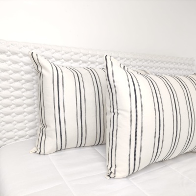 Almofadas brancas com riscas pretas sobre cama branca