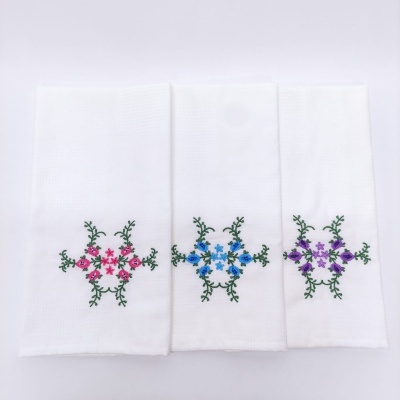 Três toalhas brancas com bordados florais coloridos