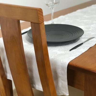 Mesa de jantar em madeira com prato cinza e copo de vidro.