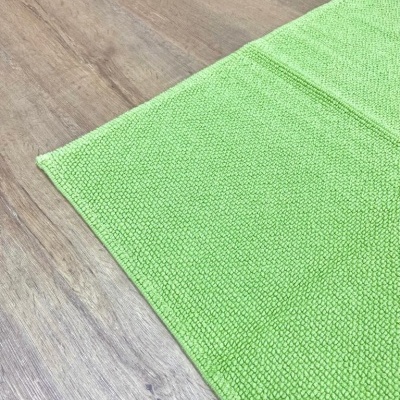 Tapete verde claro com textura de pequenos nódulos quadrados sobre chão de madeira clara