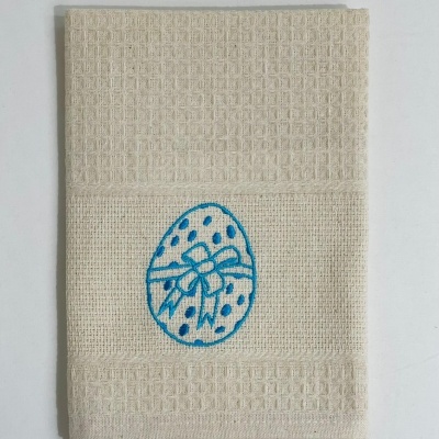 toalha de cozinha bege com bordado azul de ovo e laço