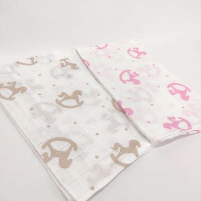 Dois panos de tecido branco com padrão de cavalinhos de balanço em bege e rosa