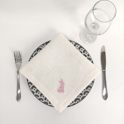 Mesa posta com prato decorado, guardanapo bordado, talheres e copo