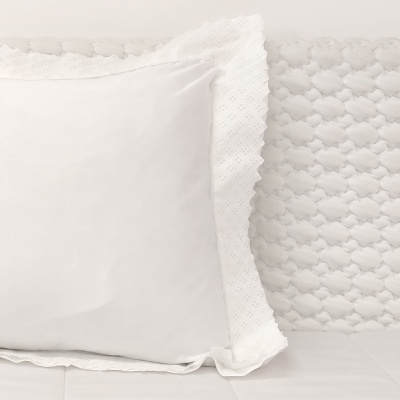 almofada branca com bordado ao redor sobre tecido texturado branco