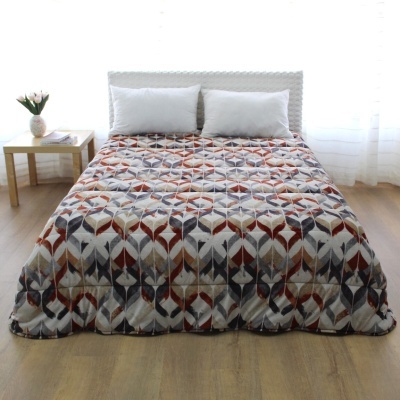 Cama com cobertura acolchoada geométrica colorida em quarto claro.