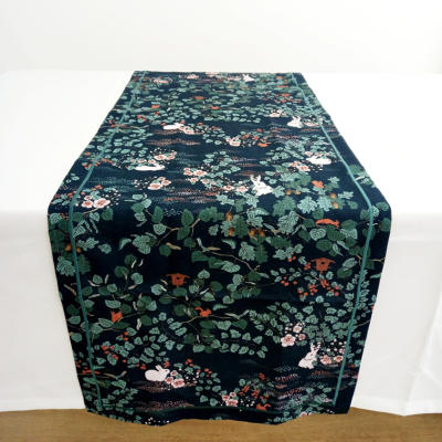 Passadeira de mesa azul escuro com padrão de folhas e flores coloridas