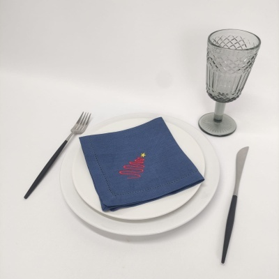 Conjunto de louça branca com guardanapo azul e copo cinza texturizado