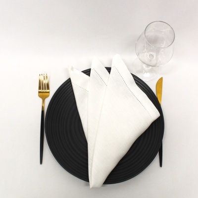 Mesa posta com prato preto, guardanapo branco, talheres pretos e dourados, e copo de vidro