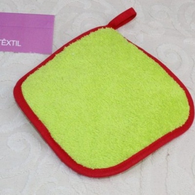 Esponja ou toalha pequena quadrada verde-limão com borda vermelha e laço, sobre tecido branco e cartão 'AG TEXTIL'