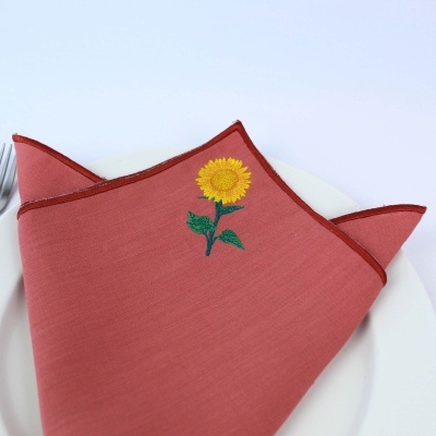 Guardanapo tecido cor de tijolo com bordado girassol amarelo e verde