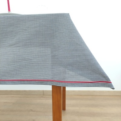 Toalha de mesa vichy preto e branco com linha vermelha sobre mesa de madeira