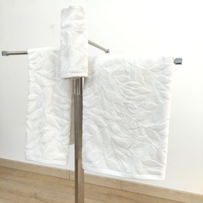 Conjunto de toalhas brancas com padrão de folhas, penduradas em suportes metálicos