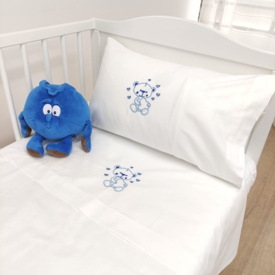 Cama de bebé branca com bordado azul de ursinho e peluche azul