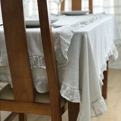 Mesa de jantar em madeira com toalha bege rendada e cadeiras de madeira