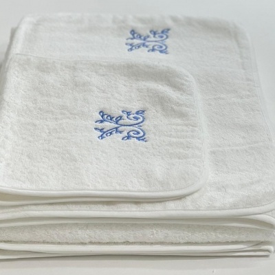 Toalhas de banho brancas com bordado azul dobradas