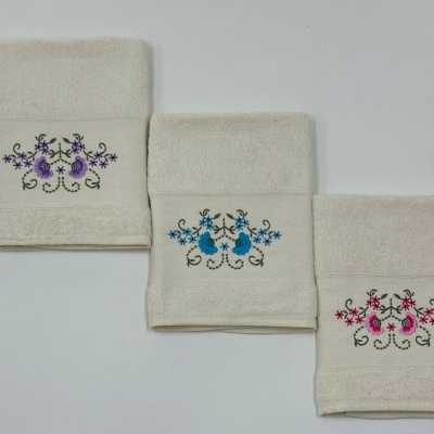 Três toalhas de rosto brancas com bordados florais coloridos