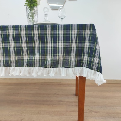 Toalha de mesa xadrez azul e verde com borda branca franzida sobre mesa de madeira