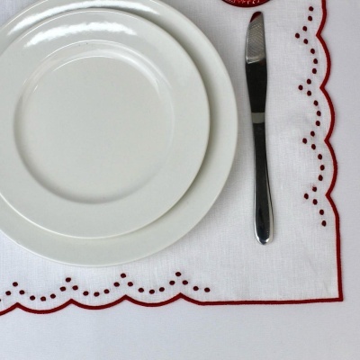 Conjunto de pratos brancos e faca sobre guardanapo branco com borda vermelha