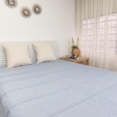 cama com edredão azul e almofadas bege num quarto com decoração minimalista e espelhos redondos na parede
