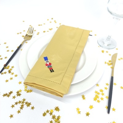 Guardanapo amarelo com bordado de soldadinho em prato branco e talheres