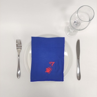 Mesa posta com talheres, prato, guardanapo azul bordado e copo