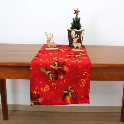 Caminho de mesa natalício vermelho com padrões dourados e verdes e decorações de natal em madeira e pinheiro artificial