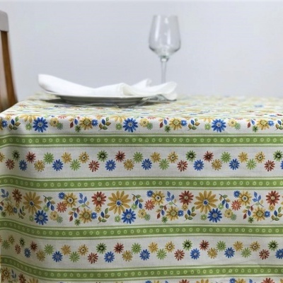 Toalha de mesa floral colorida numa mesa com cadeira de madeira, guardanapo branco e taça de vidro