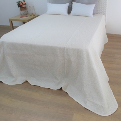 Cama com colcha branca e almofadas brancas ao lado de mesa de madeira com flores