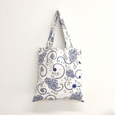 Saco de tecido branco com padrão azul pendurado na parede