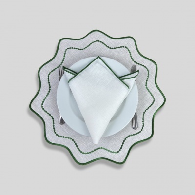 Conjunto de prato branco, guardanapo e base de tecido branco com detalhes verdes em fundo cinza