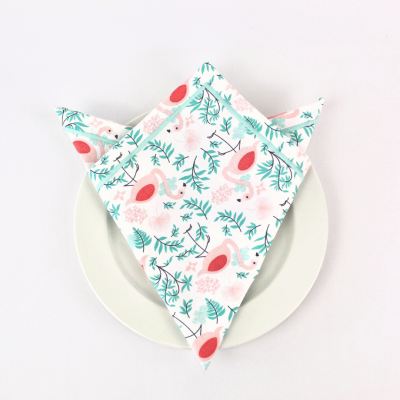 Guardanapo com padrão de flamingos e folhas verdes sobre prato branco