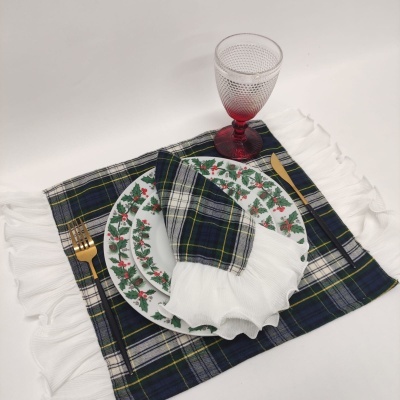 Conjunto de mesa com prato decorado, guardanapo xadrez azul com franja branca, talheres dourados e copo vermelho